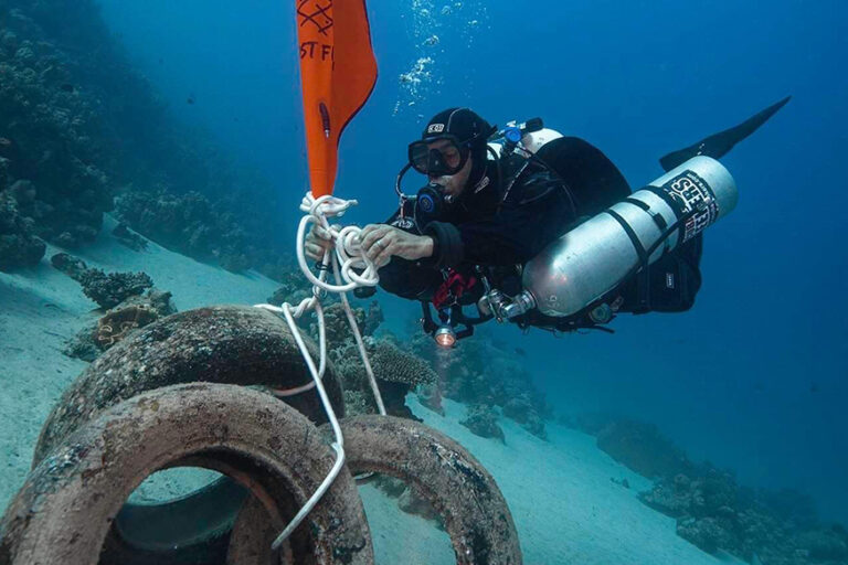 Ghost Diving - Diver recovers tyres with lift bag from ocean floor in Dahab